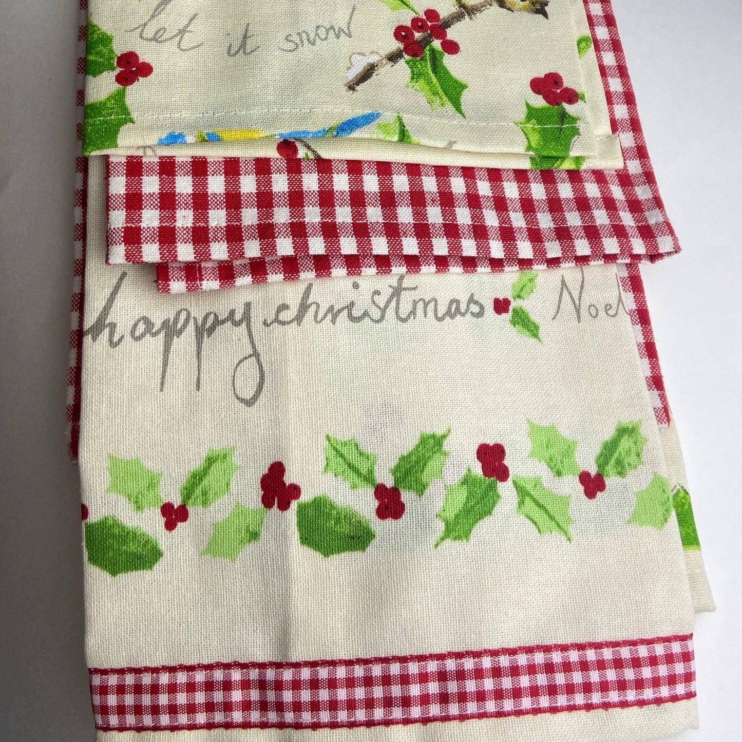 Set of three fabric towels with Christmas designs on a white surface
