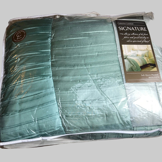 Packaged teal comforter with brand label on a bed with white bedding.