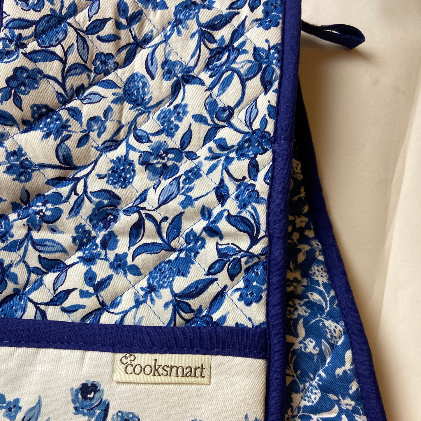 Blue floral patterned oven mitt with 'Cooksmart' label on a white background