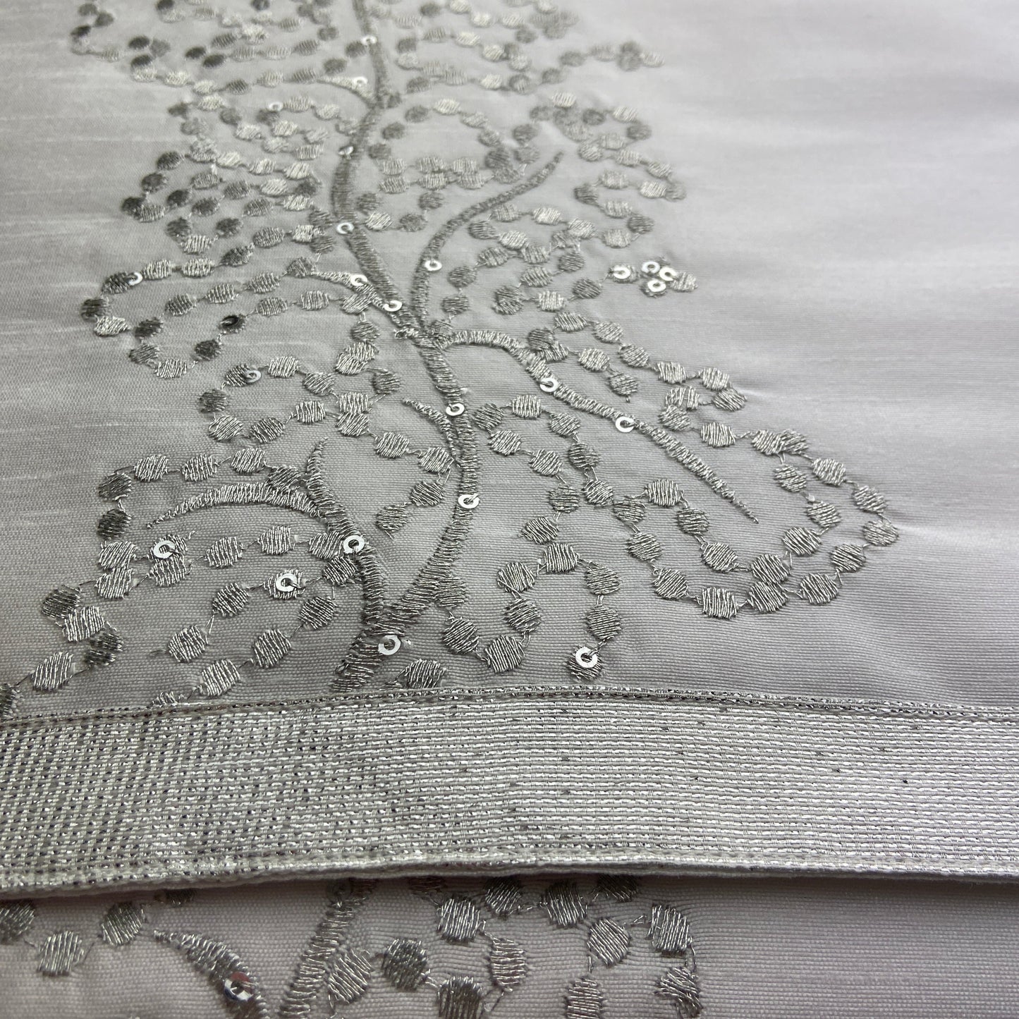 Close-up of a silver embroidered fabric with intricate patterns