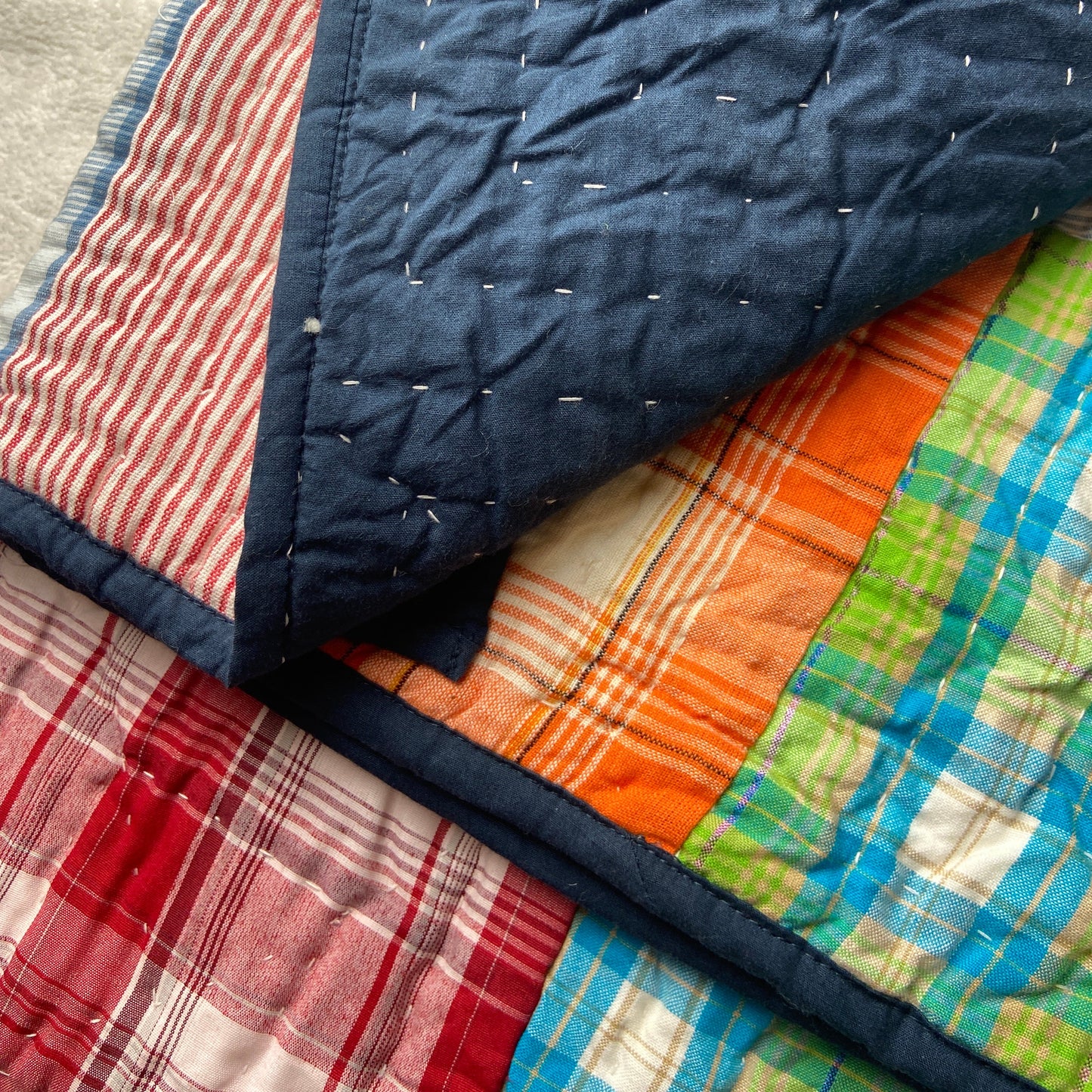 Close-up of a quilt with various patterns and colors on a bed.
