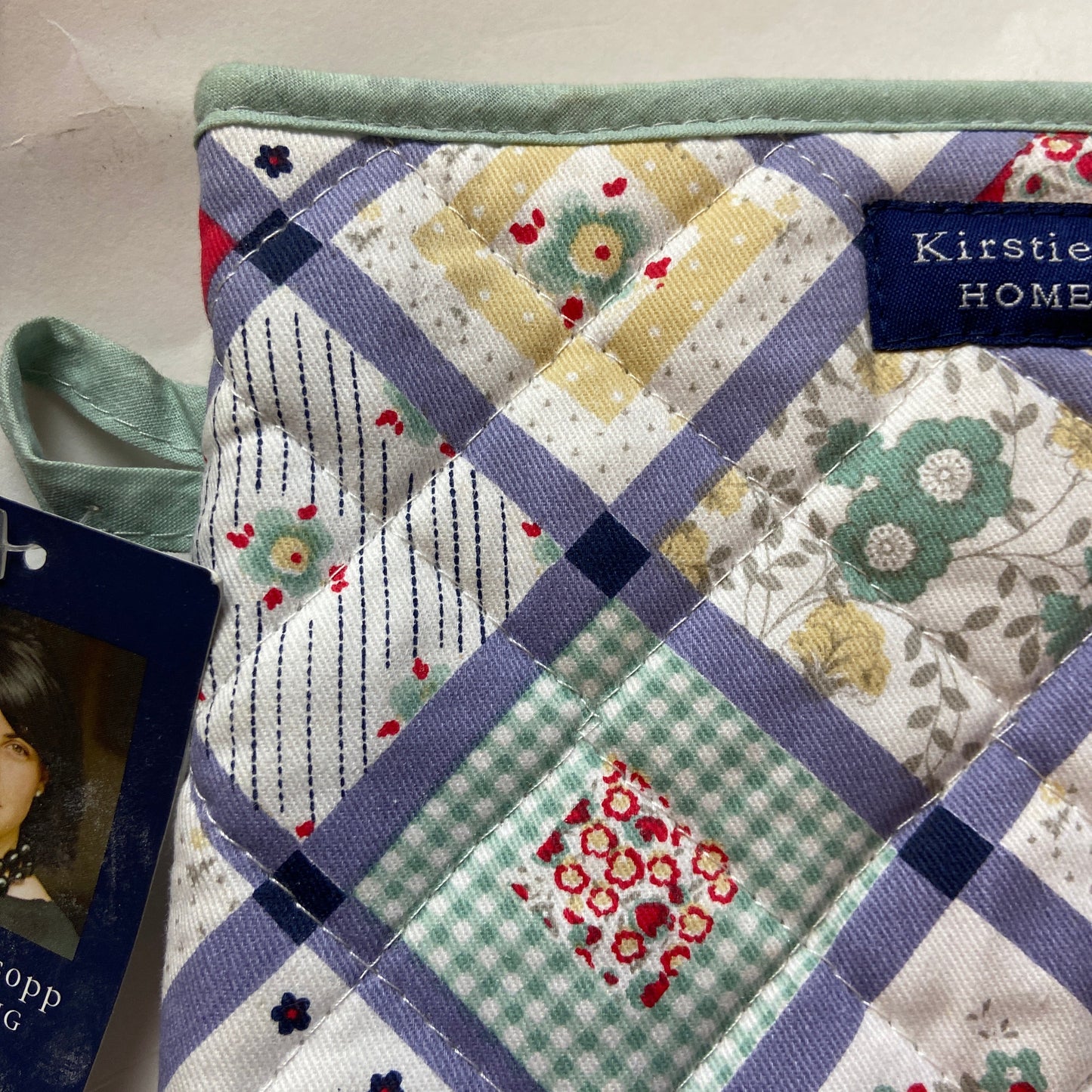 Quilt with patchwork design featuring various patterns and colors, branded 'Kirstie Home'.
