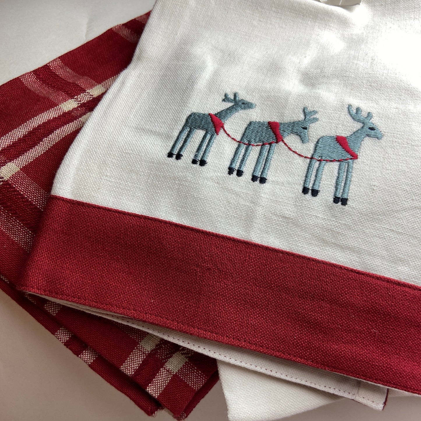 Set of towels with embroidered reindeer design on a neutral background