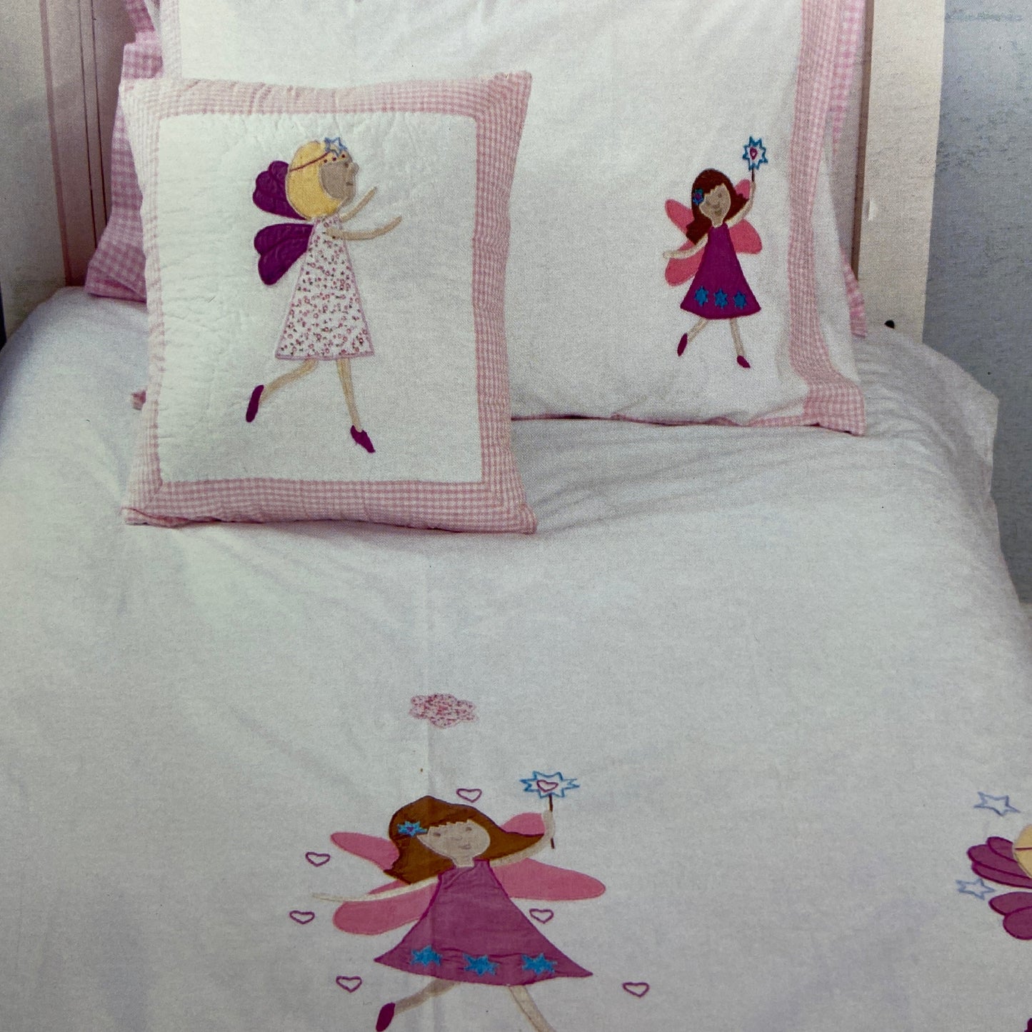 Children's bedding set with fairy designs on a bed.