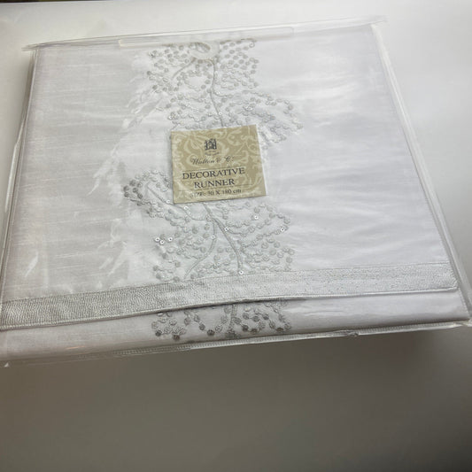 White embroidered fabric with a brand label on a white surface