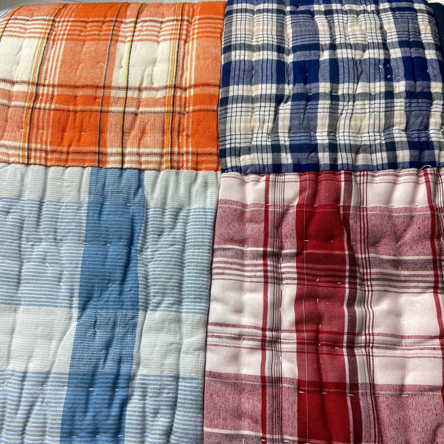 Stack of plaid fabrics in various colors on a white background