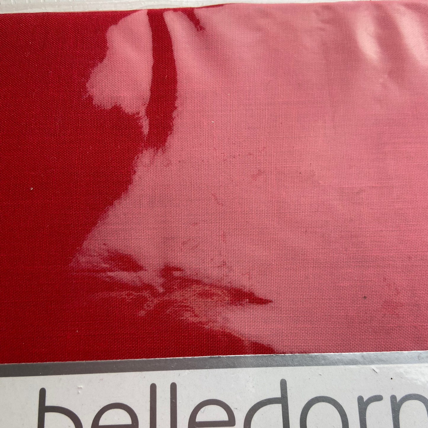 Close-up of red fabric with 'belledorm' branding at the bottom