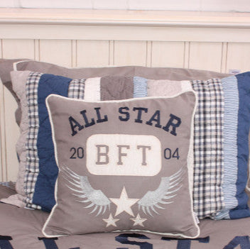 Decorative pillow with 'All Star BFT' text on a bed with plaid and checkered pillows.