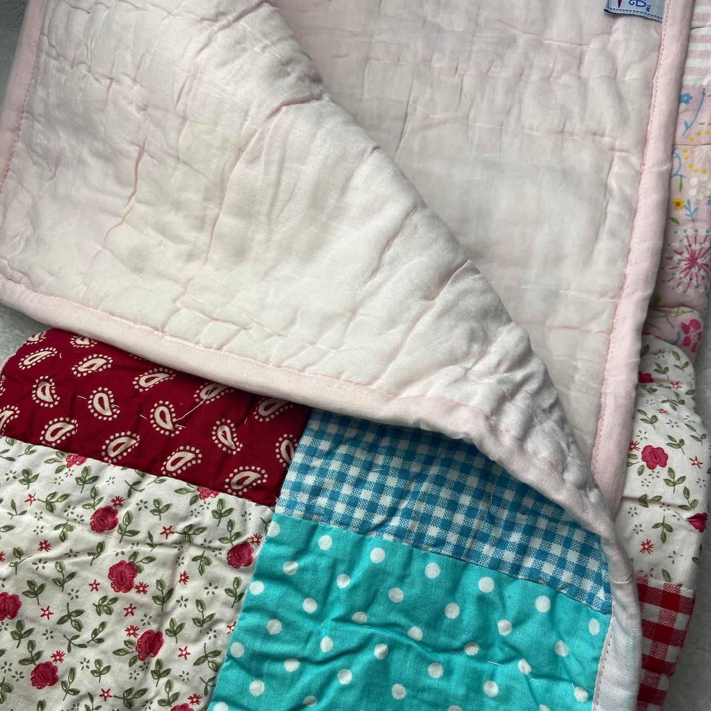 Patchwork quilt with various patterns including floral, polka dot, and checkered.