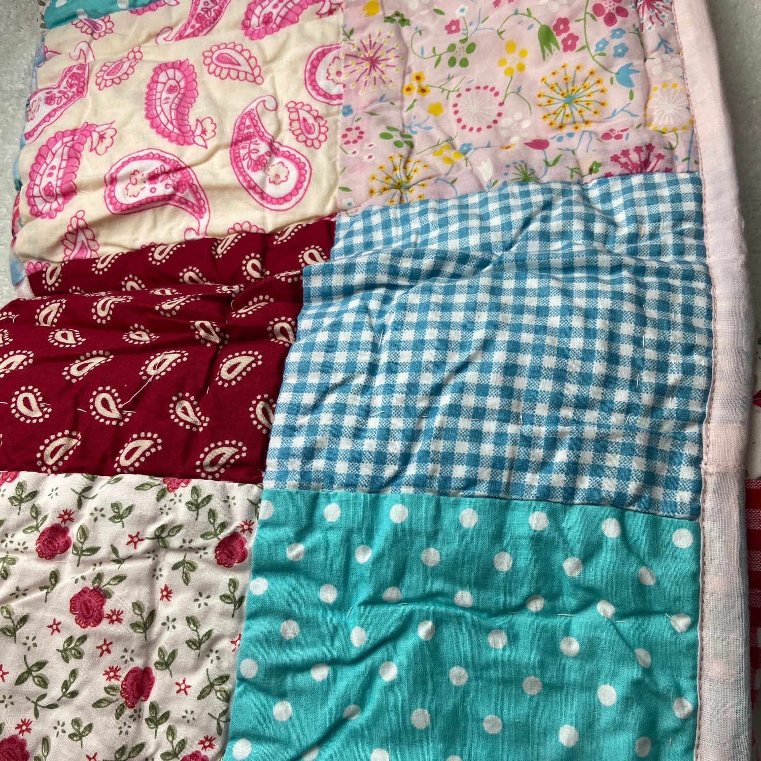 Patchwork quilt with various patterns including floral, checkered, and polka dot.