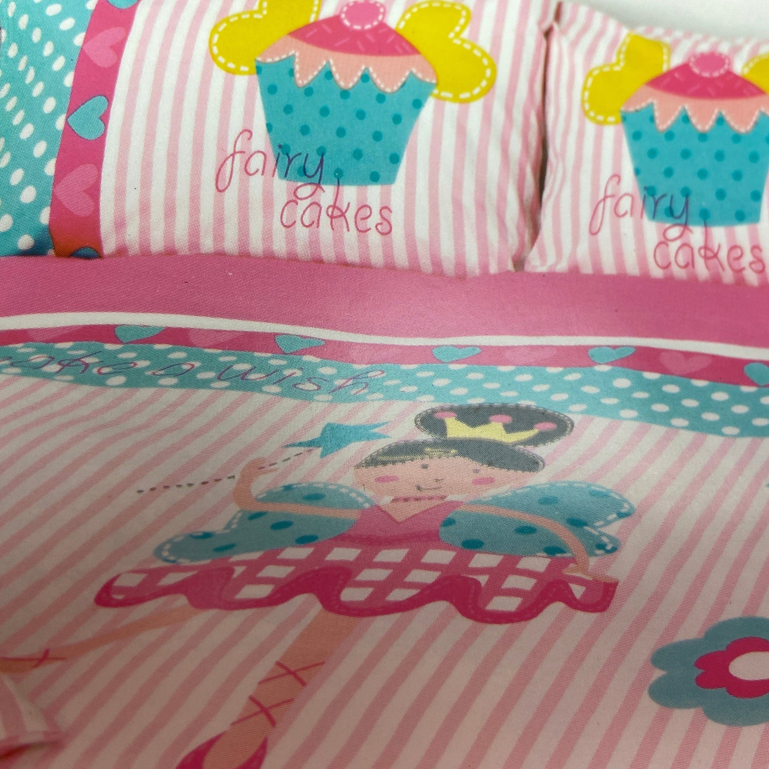 Children's bedding set with fairy and cupcake designs on a pink and white striped background.