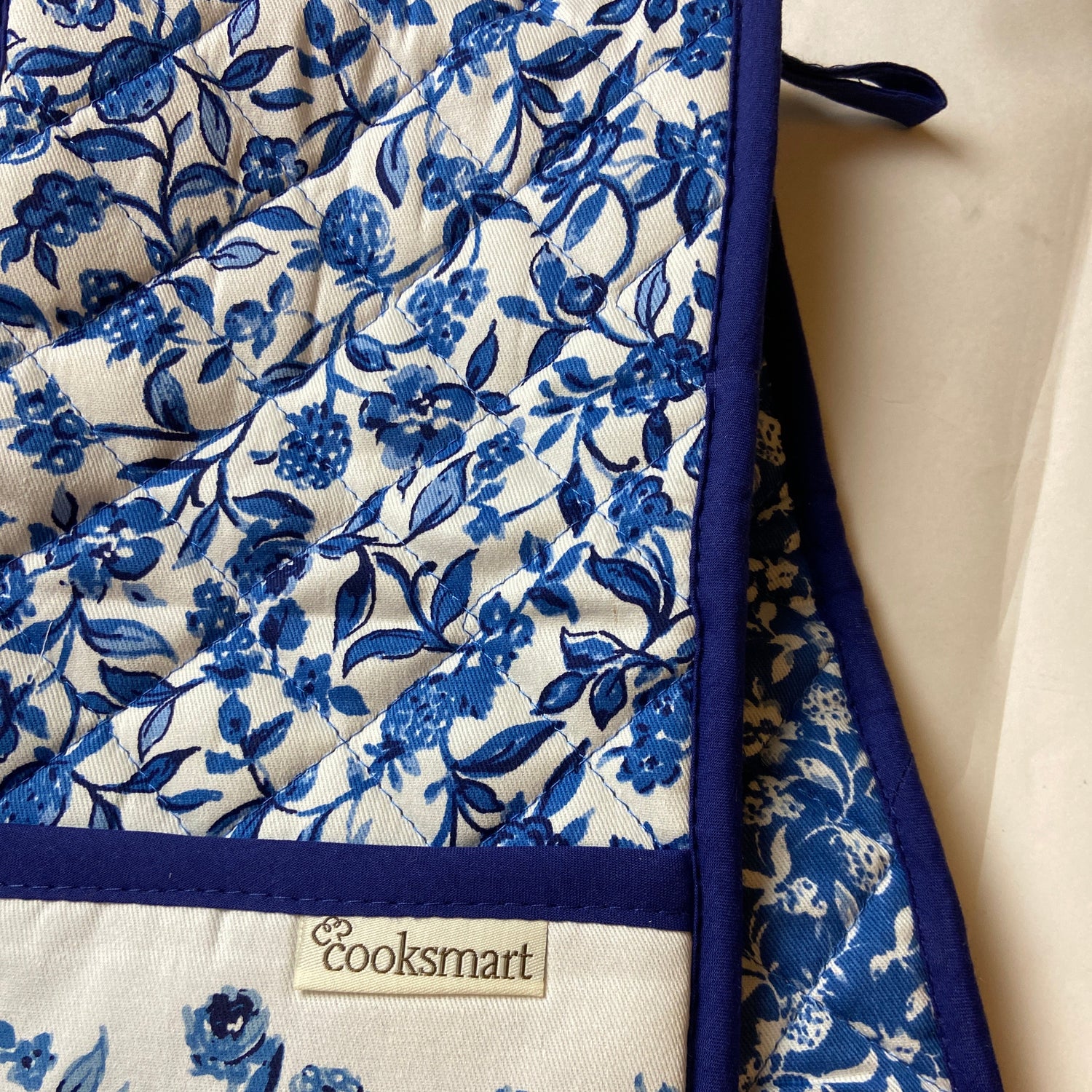 Blue floral patterned oven mitt with 'Cooksmart' label on a white background