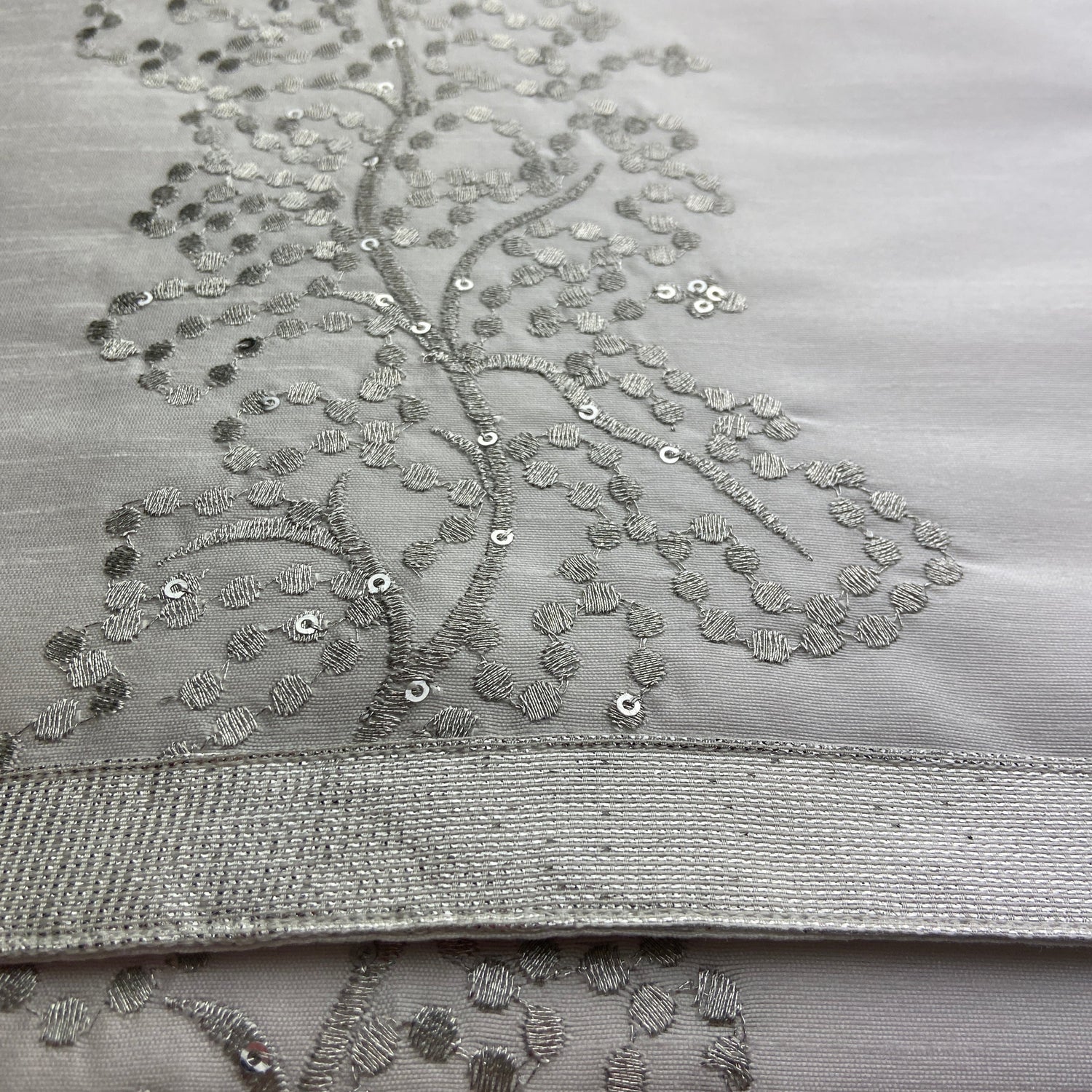 Close-up of a silver embroidered fabric with intricate patterns