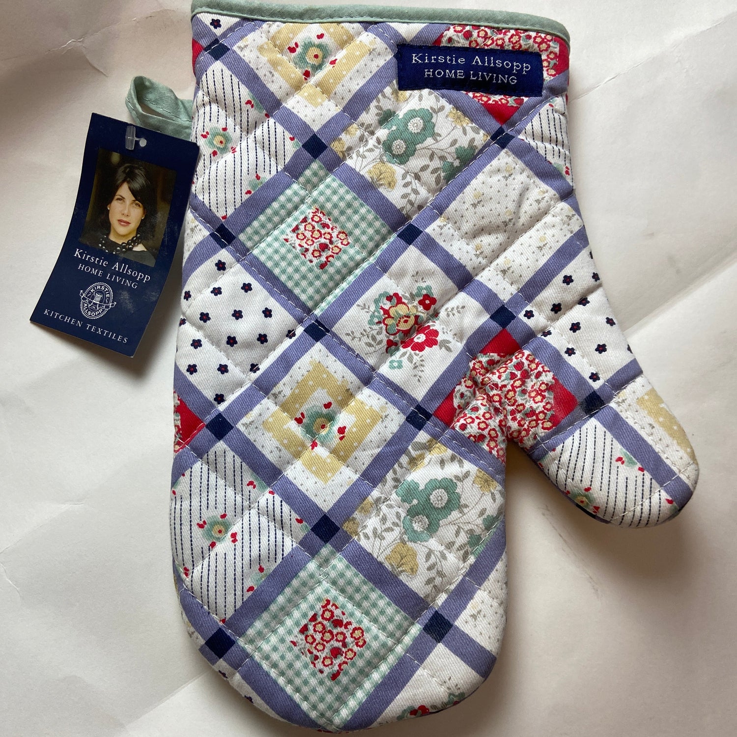 Quilted oven mitt with patchwork design on a white background