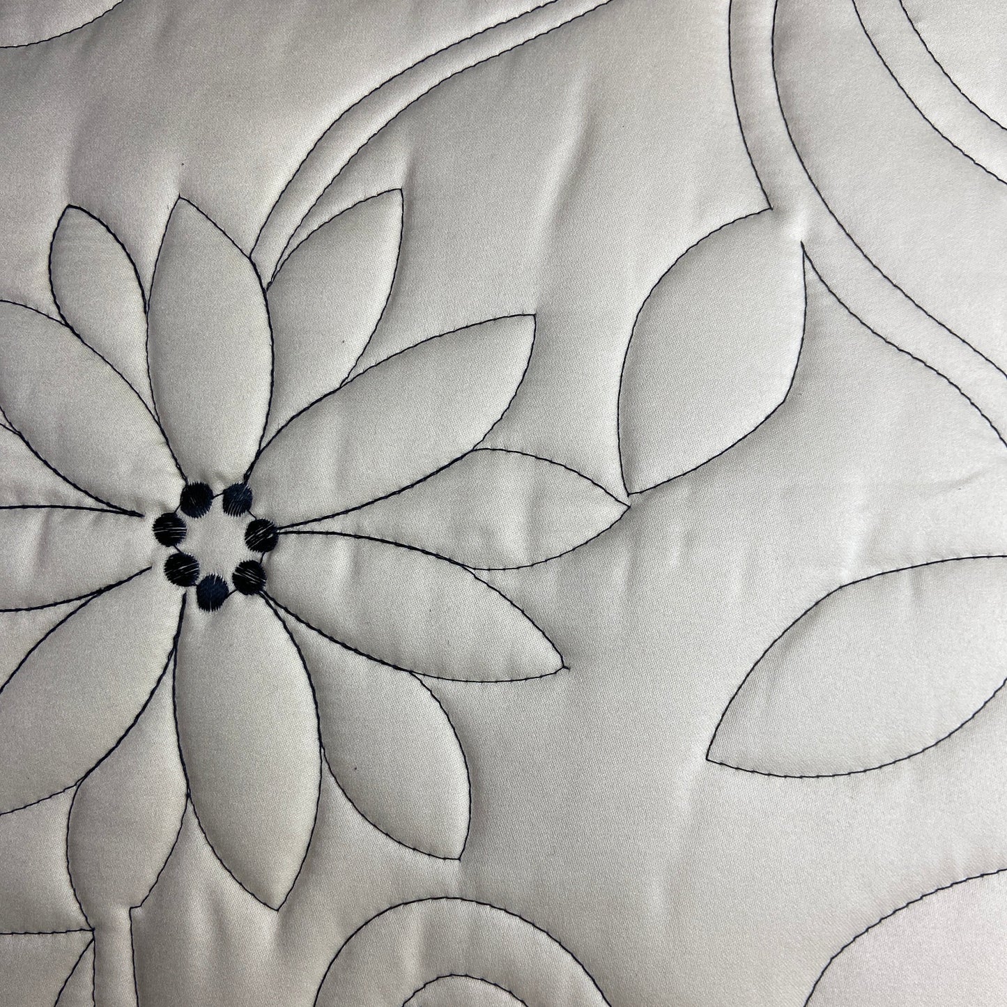 Close-up of a quilt with floral pattern and swirling lines