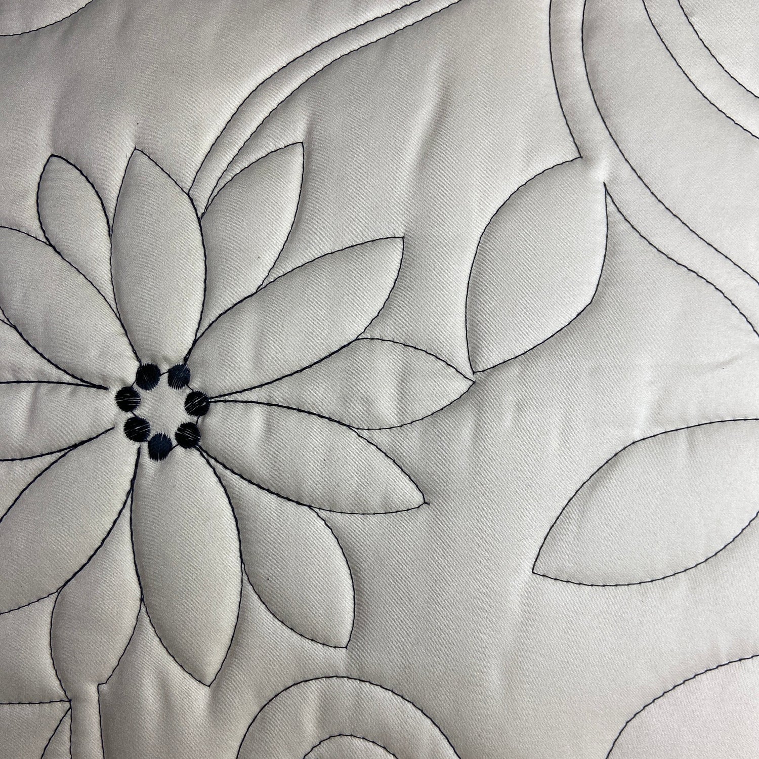 Close-up of a quilt with floral pattern and swirling lines