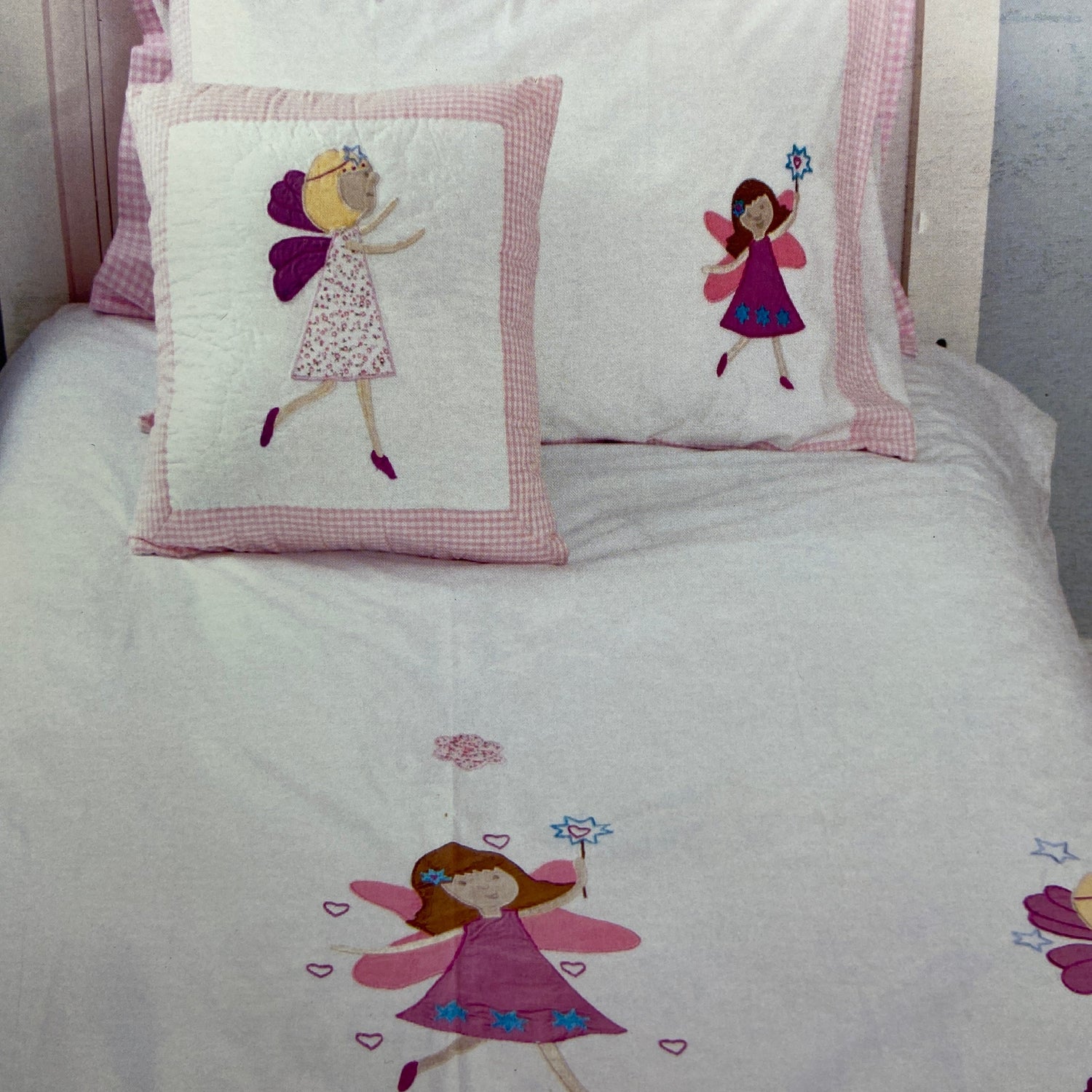 Children's bedding set with fairy designs on a bed.