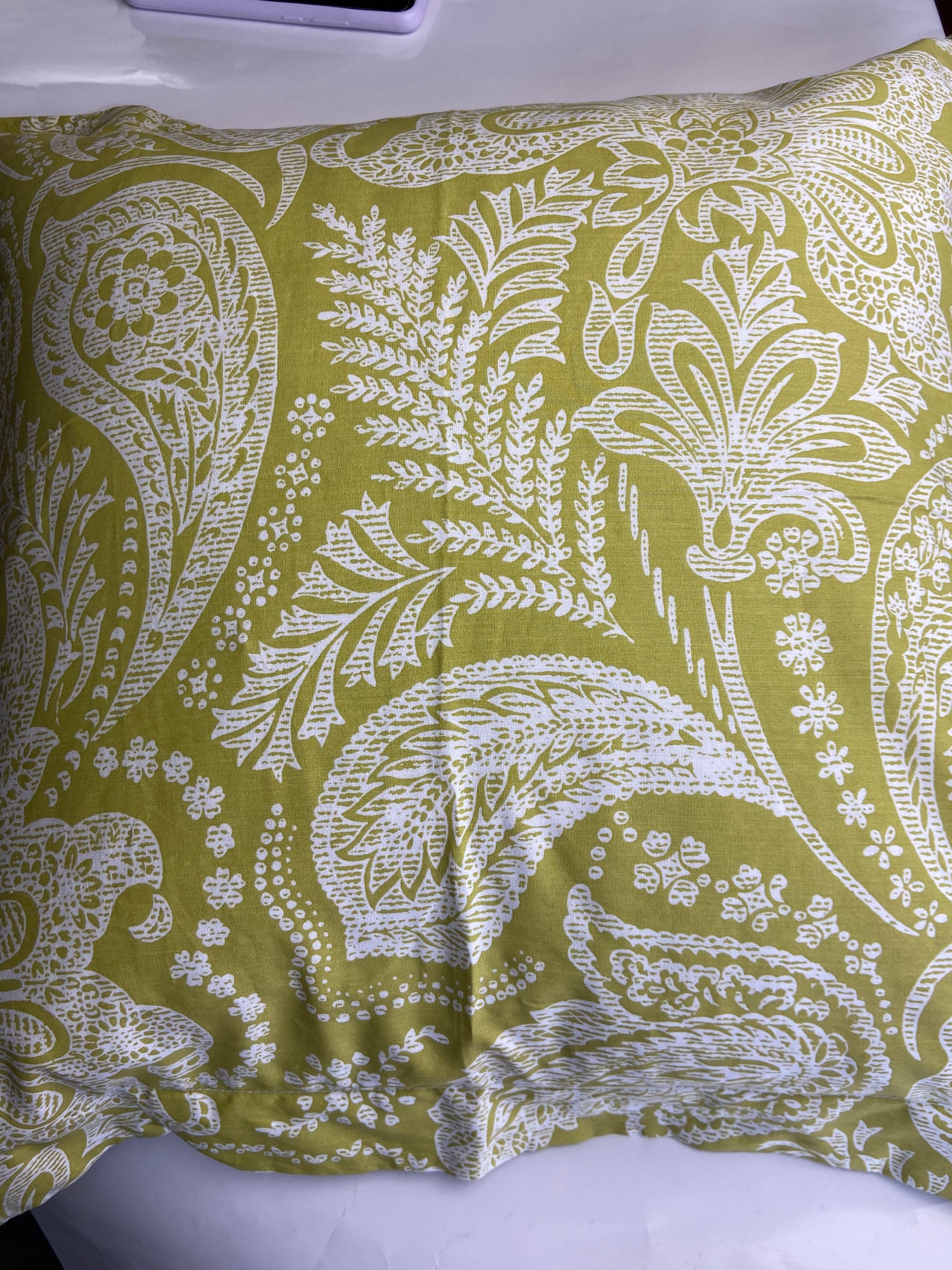 Fabric with white paisley pattern on a green background