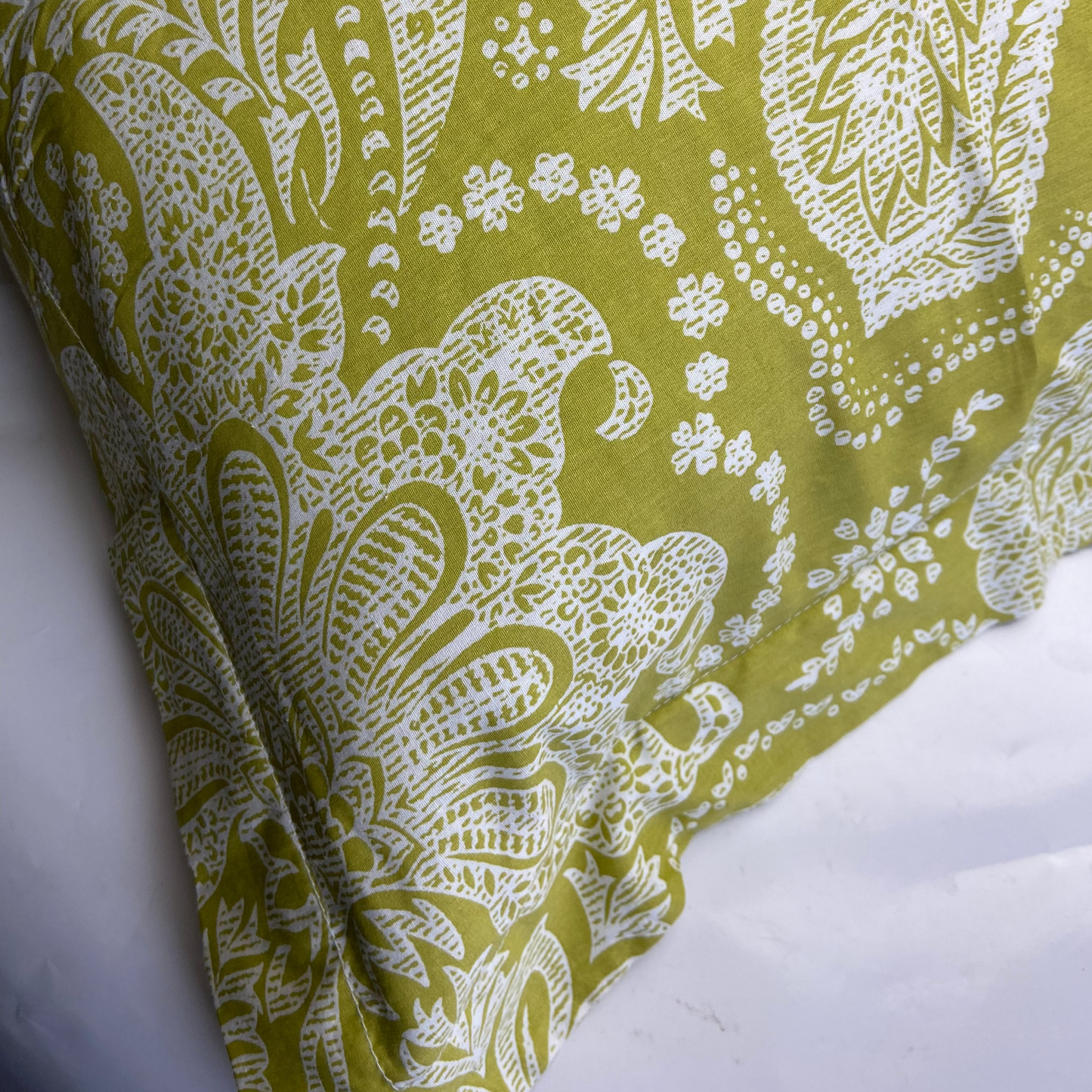 Green fabric with white paisley pattern on a white background